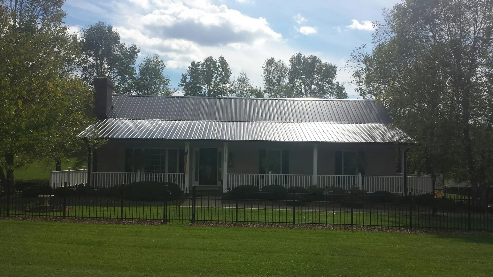 Gray metal roof on a brick ranch with a full width front porch in West Point